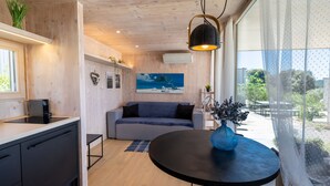 A modern kitchen with a black countertop, a grey sofa, and a round table with a blue vase. - BUQEZ ECO RESORT - Villa 13 - Seafront (Drage)