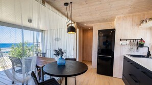 A modern kitchen with a black refrigerator, wooden cabinets, and a dining area with a round table and chairs. - BUQEZ ECO RESORT - Villa 13 - Seafront (Drage)
