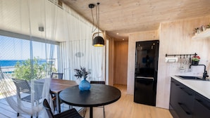 A modern kitchen with a black refrigerator, wooden cabinets, and a dining area with a round table and chairs.