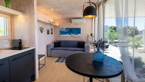 A modern kitchen with a black countertop, a grey sofa, and a round table with a blue vase.