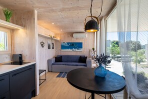 A modern kitchen with a black countertop, a grey sofa, and a round table with a blue vase. - BUQEZ ECO RESORT - Villa 13 - Seafront (Drage)