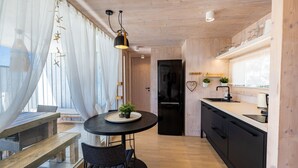 Una cocina moderna con un refrigerador negro, gabinetes de madera y una encimera negra. Hay un comedor con una mesa redonda y sillas.