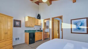 A bedroom with a large bed, wooden cabinets, a kitchenette, and a framed picture on the wall. - Cottonwood cabin next to Pond (Swan Valley)