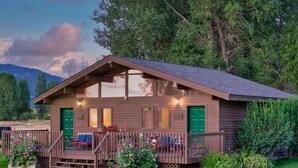 A wooden cabin with a porch, green doors, and a small garden. - Cottonwood cabin next to Pond (Swan Valley)