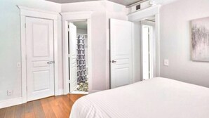 A bedroom with a bed, two white doors, and a closet with patterned curtains. - Terrific Dallas Location! 2BR w/ Wi-Fi & A/C – Knight 205 (Dallas)