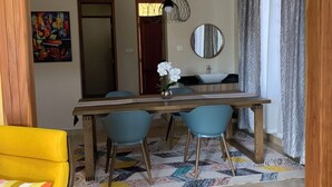 A dining area with a wooden table, blue chairs, a potted plant, and a mirror on the wall. - THEMI RIVER RETREAT- Secure 3BR Near Arusha Bypass  (Arusha)