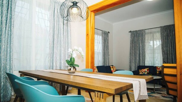 A dining area with a wooden table, teal chairs, and a hanging light fixture. - THEMI RIVER RETREAT- Secure 3BR Near Arusha Bypass  (Arusha)