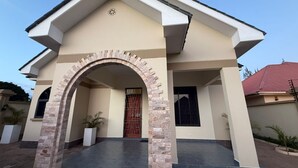 A modern house with a beige facade, a brick archway, and a red door. - THEMI RIVER RETREAT- Secure 3BR Near Arusha Bypass  (Arusha)