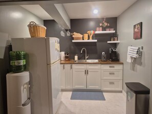 A compact kitchen with a refrigerator, sink, and a coffee maker.