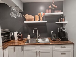 A kitchen with a wooden countertop, stainless steel sink, and various kitchen utensils.