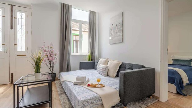 Une chambre à coucher moderne avec un lit, une table de chevet et une fenêtre avec des rideaux.