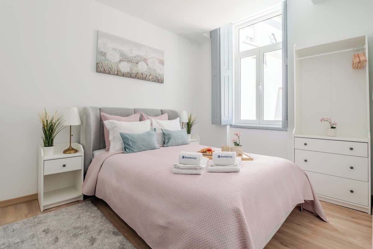Une chambre à coucher bien rangée, avec un lit, des tables de chevet, une commode, une fenêtre et une armoire.