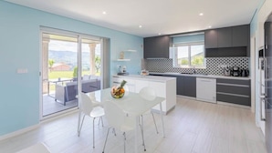 A modern kitchen with a central island, white chairs, and a dining table. - 10BR Douro Villa with Pool by HostWise (Santa Marinha do Zêzere)