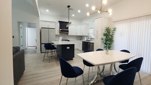 A modern kitchen with white cabinets, a central island, and a dining area with a white table and dark chairs. - 3-bedroom house in Orlando near Universal Studios (Orlando)