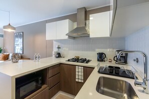 Una cocina moderna con microondas integrado, estufa y lavamanos.
