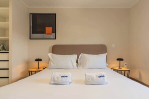 Ein Hotelzimmer mit einem Bett, zwei Nachttischen, einem Wandbild und einem gerahmten Bild.