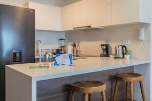 Eine moderne Küche mit einer zentralen Kochinsel, Barhocker, einer Kaffeemaschine und einem Wasserspender.