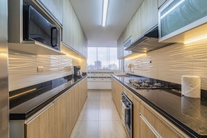 Eine moderne Küche mit Holdekor-Schränken, einer schwarzen Arbeitsplatte und Blick auf die Stadt durch große Fenster.