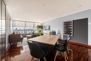Ein modernes Interieur mit einem Holztisch, schwarzen Stühlen, einer Couch und Blick auf die Stadt.