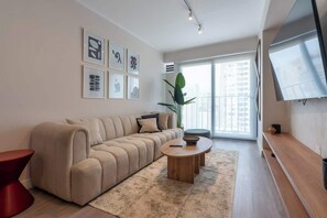 Ein modernes Wohnzimmer mit einer Couch, einem Couchtisch und einem Fernseher.