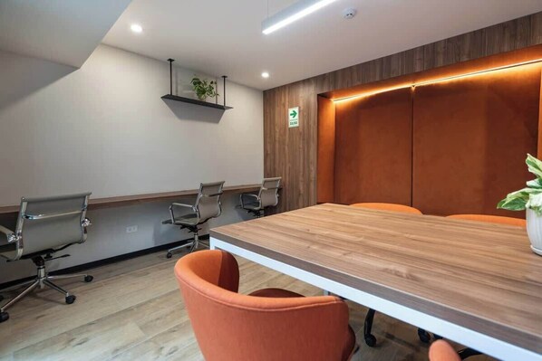 Ein Konferenzraum mit einem Holztisch, vier Bürostühlen und einem Blumentopf.