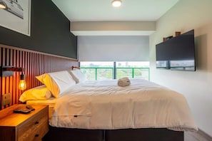 Ein Hotelzimmer mit Bett, Nachttisch, Fernseher und einem Fenster mit Blick.