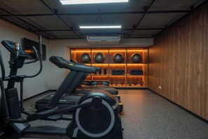 A gym with treadmills, a stationary bike, and a wall of exercise equipment. - Geko| Sleek 1BR w/Balcony near Spots in Miraflores (Lima)
