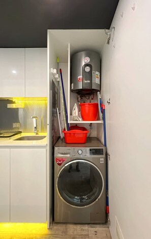 Un espacio práctico para la lavandería con lavadora, calentador y estantes de almacenamiento.