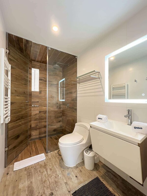 Une salle de bain moderne équipée d’une douche, de toilettes, d’un lavabo et d’un miroir.