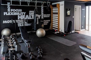 A gym with exercise equipment, a punching bag, and motivational words on the wall.