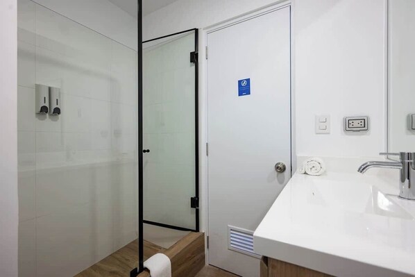 Une salle de bain moderne avec une douche à parois de verre, un lavabo blanc et un porte-serviettes.