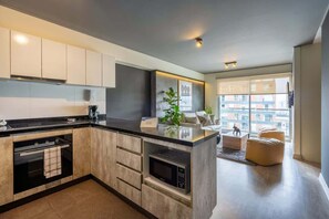 Eine moderne Küche mit integrierten Geräten, ein Essbereich mit Ausblick und ein Wohnbereich mit Sofa und Hocker.