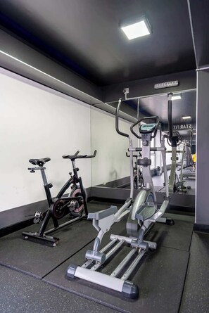 Ein Fitnessraum mit Trainingsgeräten, darunter ein Ergometer, ein Crosstrainer und Kraftgeräte.
