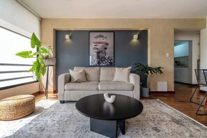 Una sala de estar moderna con un sofá, una mesa de centro y una gran obra de arte en la pared.