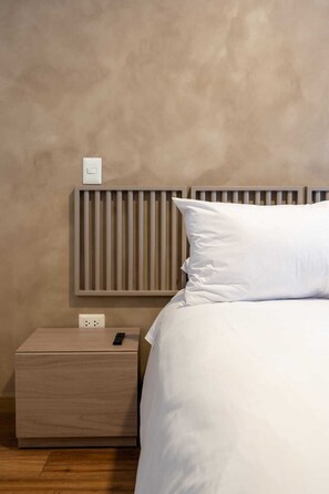 Ein Schlafzimmer mit einem Bett, einem Nachttisch, einer Steckdose und einem Lichtschalter.