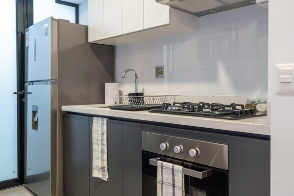A modern kitchen with a built-in oven, a gas stove, and a stainless steel refrigerator.
