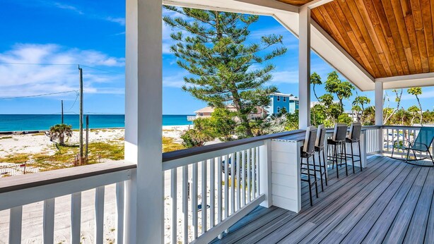 A covered outdoor deck with a view of the beach and ocean.