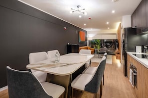 A modern kitchen with a dining area, a built-in oven, and a large window. - Geko | Inspiring 2BR near Malecon w/ Balcony (Miraflores)