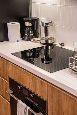 A modern kitchen with a black induction cooktop, a coffee maker, and a kettle. - Geko | Inspiring 2BR near Malecon w/ Balcony (Miraflores)