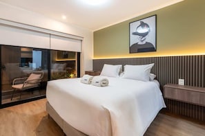 A modern hotel room with a large bed, a glass door leading to a balcony, and a framed artwork on the wall. - Geko | Inspiring 2BR near Malecon w/ Balcony (Miraflores)