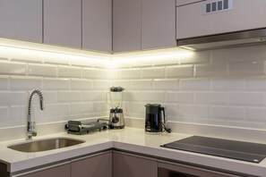 Una cocina moderna con azulejos blancos tipo metro, electrodomésticos de acero inoxidable y una encimera negra elegante.