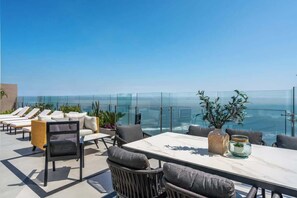 A rooftop terrace with outdoor seating, a table, and a view of the ocean. - Geko | Refined 1BR Modern Stay near the Malecón (Barranco)