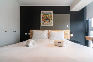 Hotellihuone, jossa on sänky, juliste seinällä ja ikkuna.