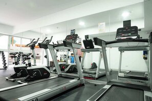 Un gimnasio con cintas de correr, elípticas y equipo de pesas.