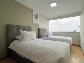 Un dormitorio con dos camas, un ventanal grande y vistas a la ciudad.