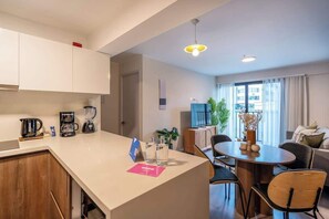 Una cocina moderna con comedor, televisor y vista a la ciudad.
