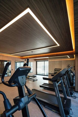 Ein Fitnessraum mit Laufbändern, Ergometer und einem großen Spiegel.