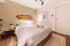 Ein Schlafzimmer mit einem Bett, einem Nachttisch, einer Wandleuchte und einer Tür.