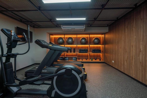 Un gimnasio con cintas de correr, elípticas y una pared de equipo de ejercicio.