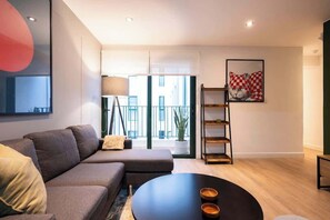 A modern living room with a sofa, a round coffee table, a floor lamp, and a framed artwork on the wall. - Geko | Elegant 1BR w/ Free Parking in Barranco (Barranco)